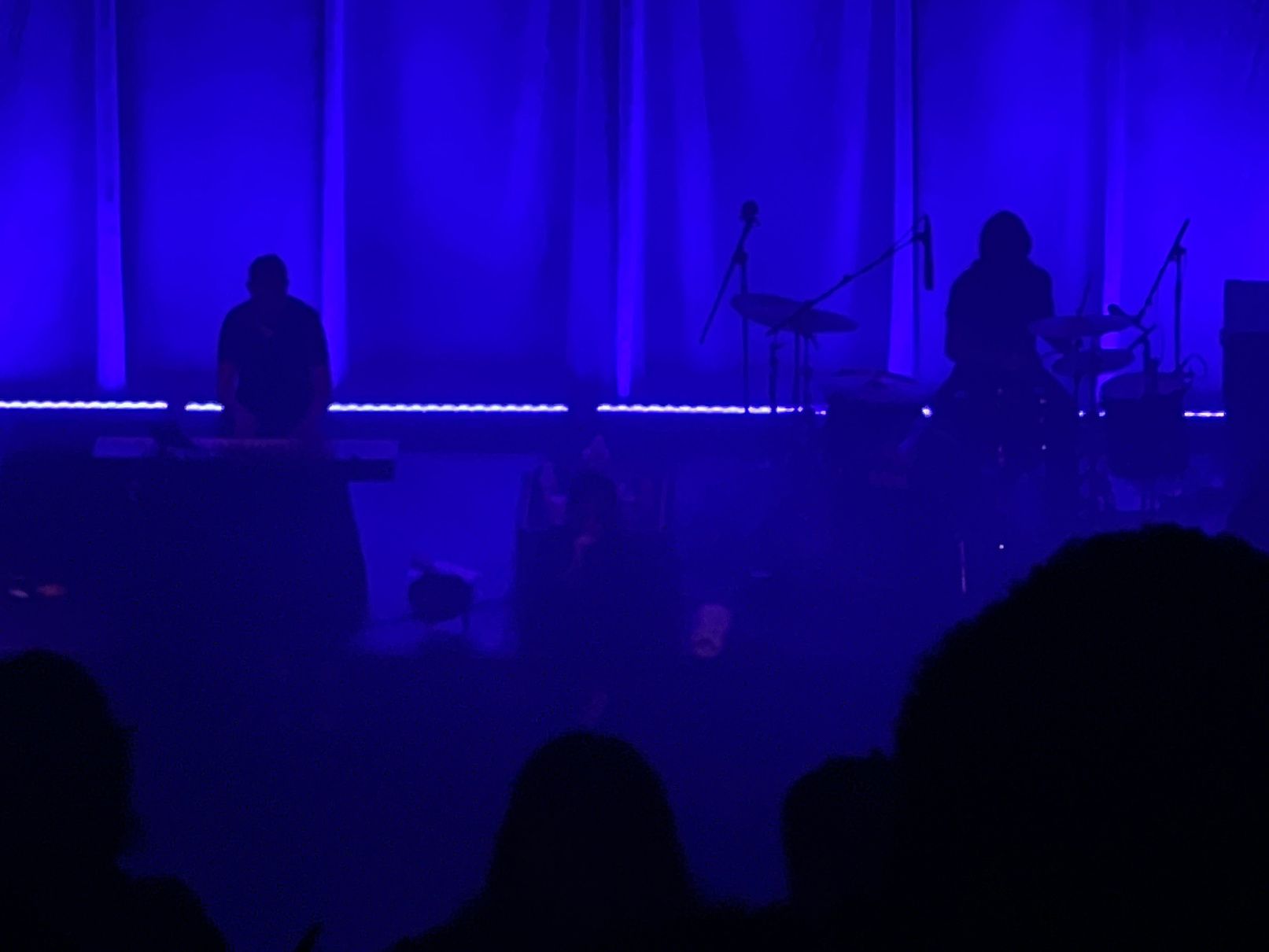 Two silhouettes against blue stage light